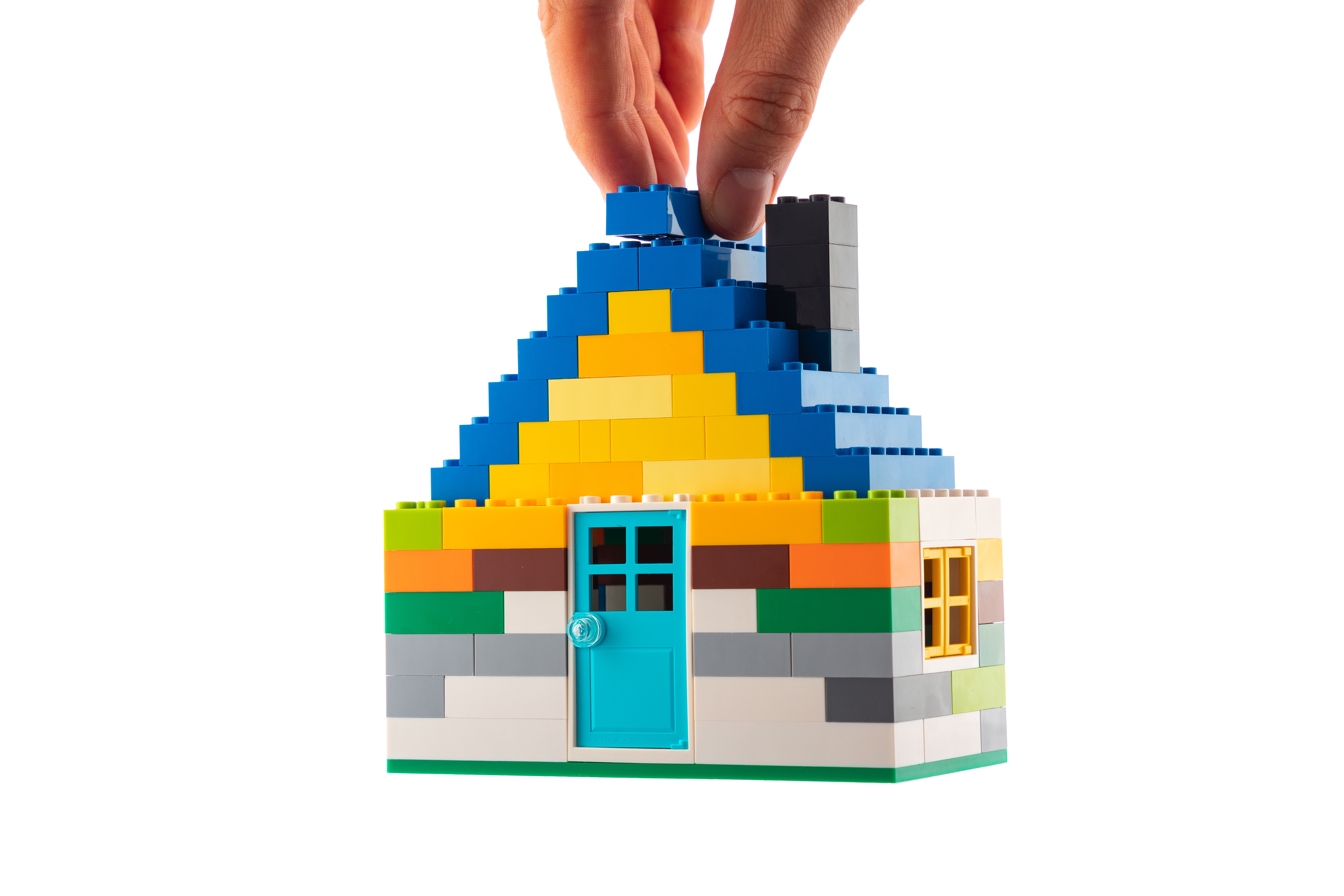 House made of classic building blocks, white studio background.